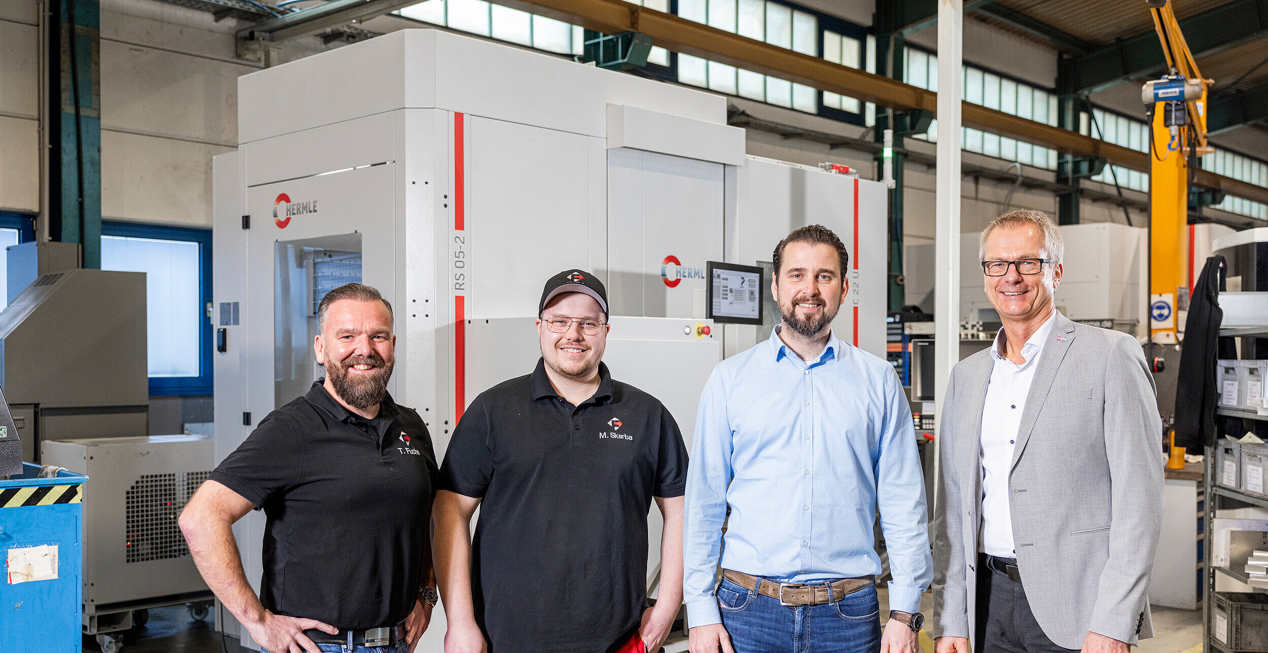 FWM employees in front of their HERMLE machining centre C 22 with RS 05-2 robot system