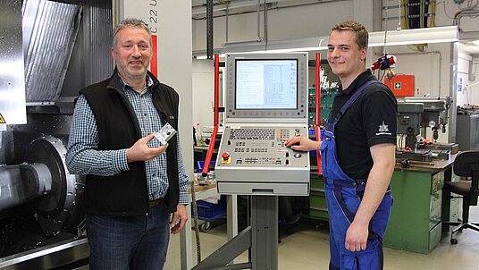 Von links Uwe Wambach, Betriebsleiter, und rechts Andreas Theis, Industriemechaniker, beide von Oculus Optikgeräte GmbH in Wetzlar, vor dem 5-Achsen- CNC-Hochleistungs-Bearbeitungszentrum C 22 U von Hermle